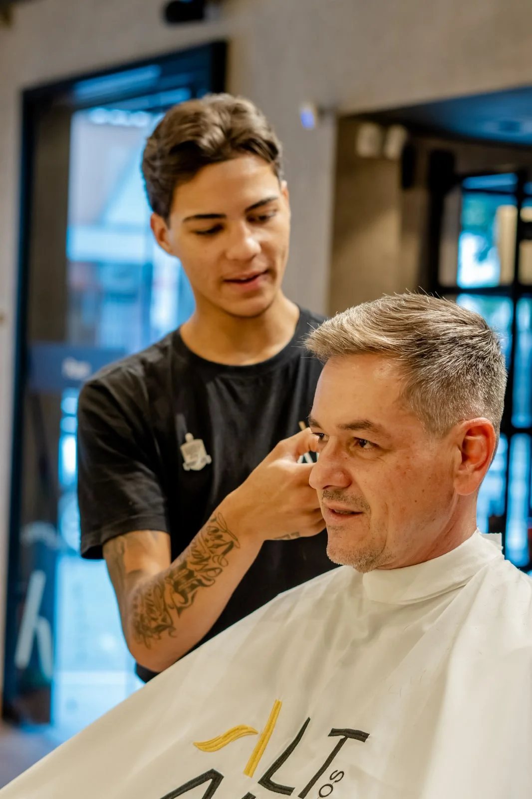 Barbeiro atendendo um cliente de cabelo grisalho