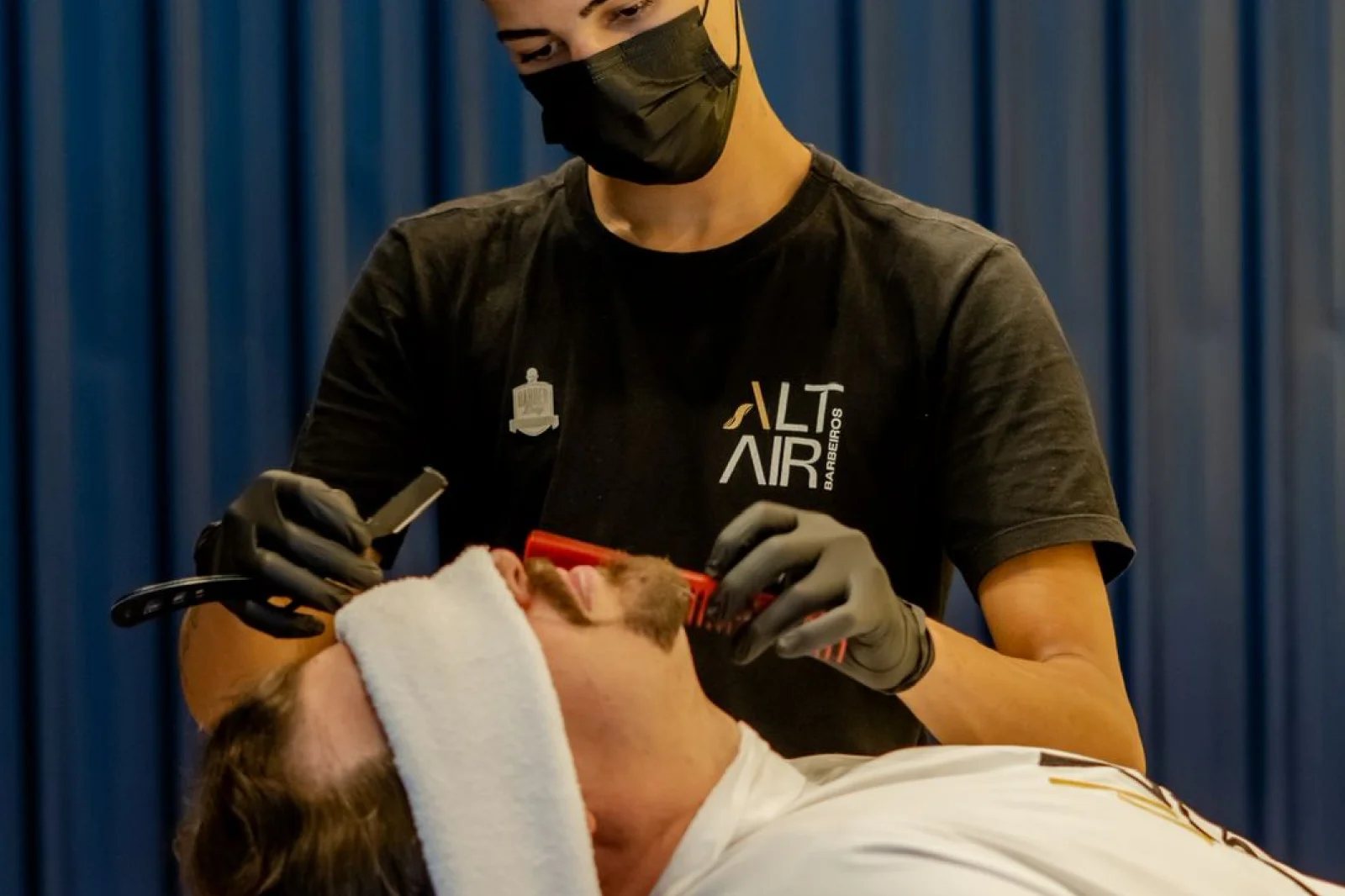 Barbeiro de luvas fazendo a barba de um cliente