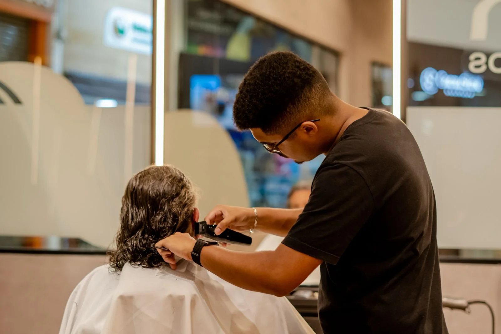 Barbeiro passando a máquina no cabelo de um cliente